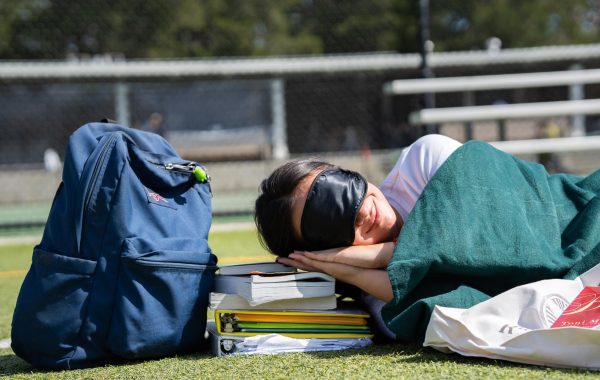 Liu takes a midday nap on the field, using her school materials as a pillow.