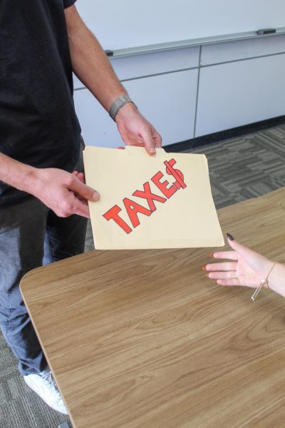 Spence distributes his taxes to students in class.